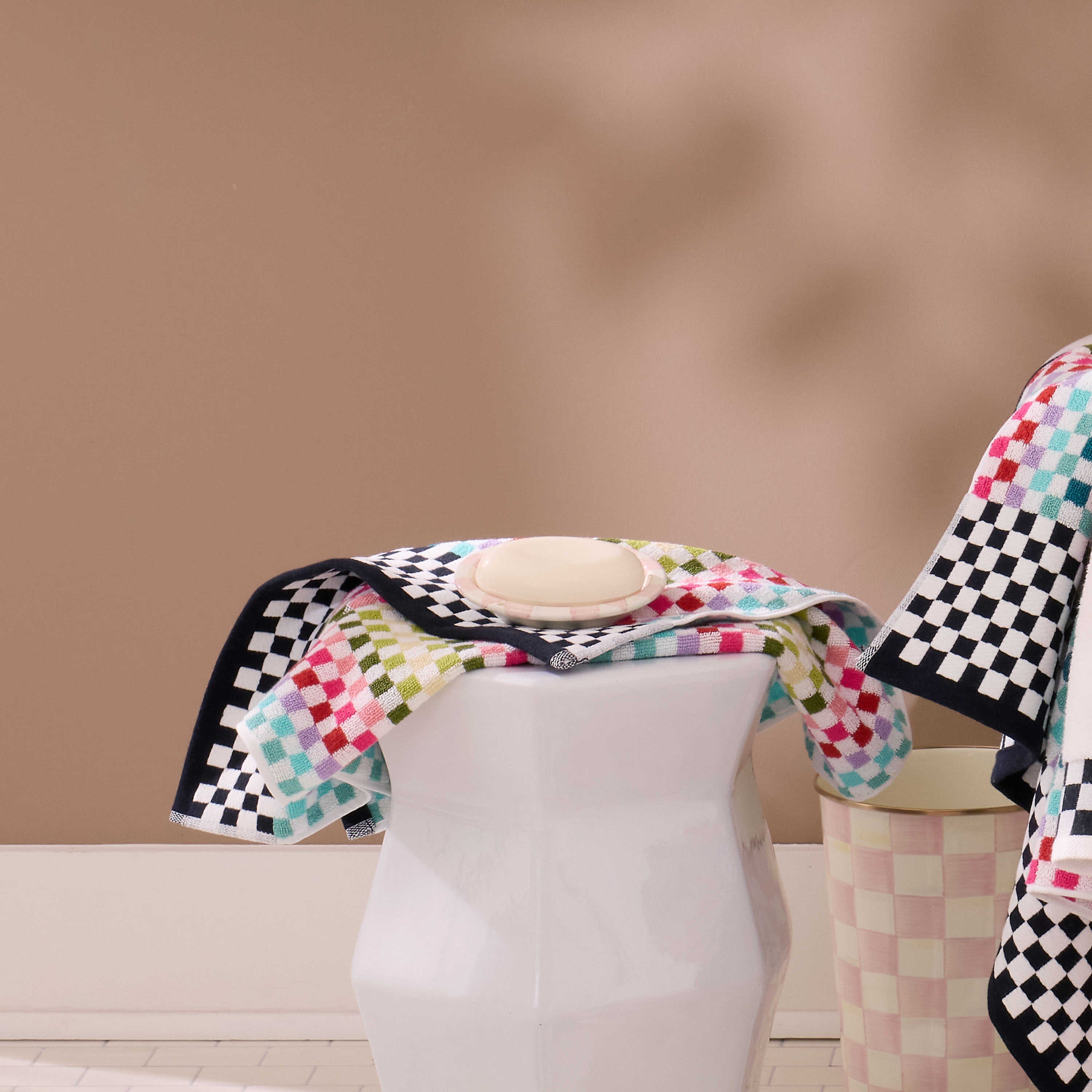 Hand-painted Rosy Check soap dish with a bar of soap on a colorful checkered towel.