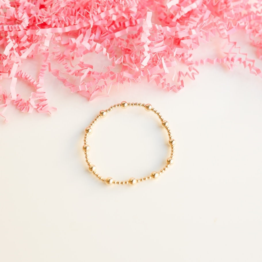 Gold-filled beaded bracelet on elastic string with a lively geometric pattern.
