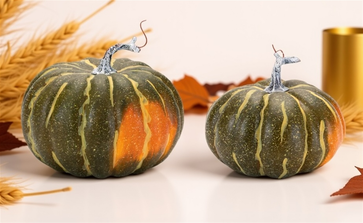 Two green and orange decorative styrofoam pumpkins with silver stems on a white surface.