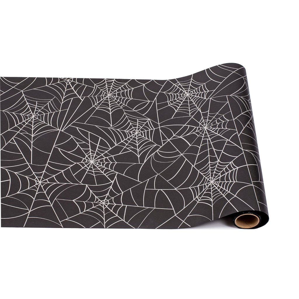 Black paper table runner with a white spiderweb pattern, partially unrolled.