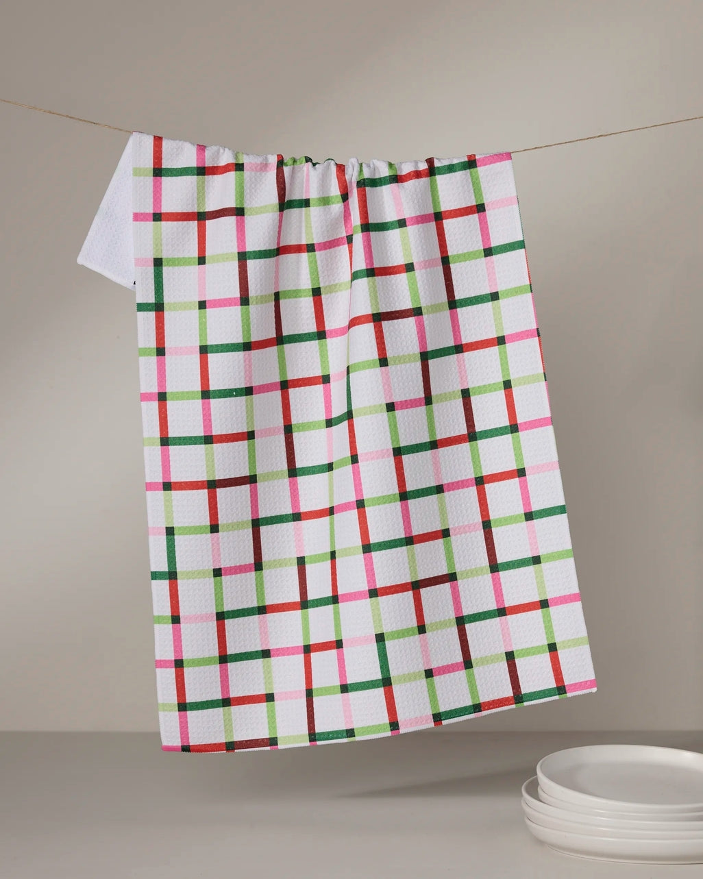 Holiday-themed tea towel with waffle weave construction in red featuring festive snowflake pattern.