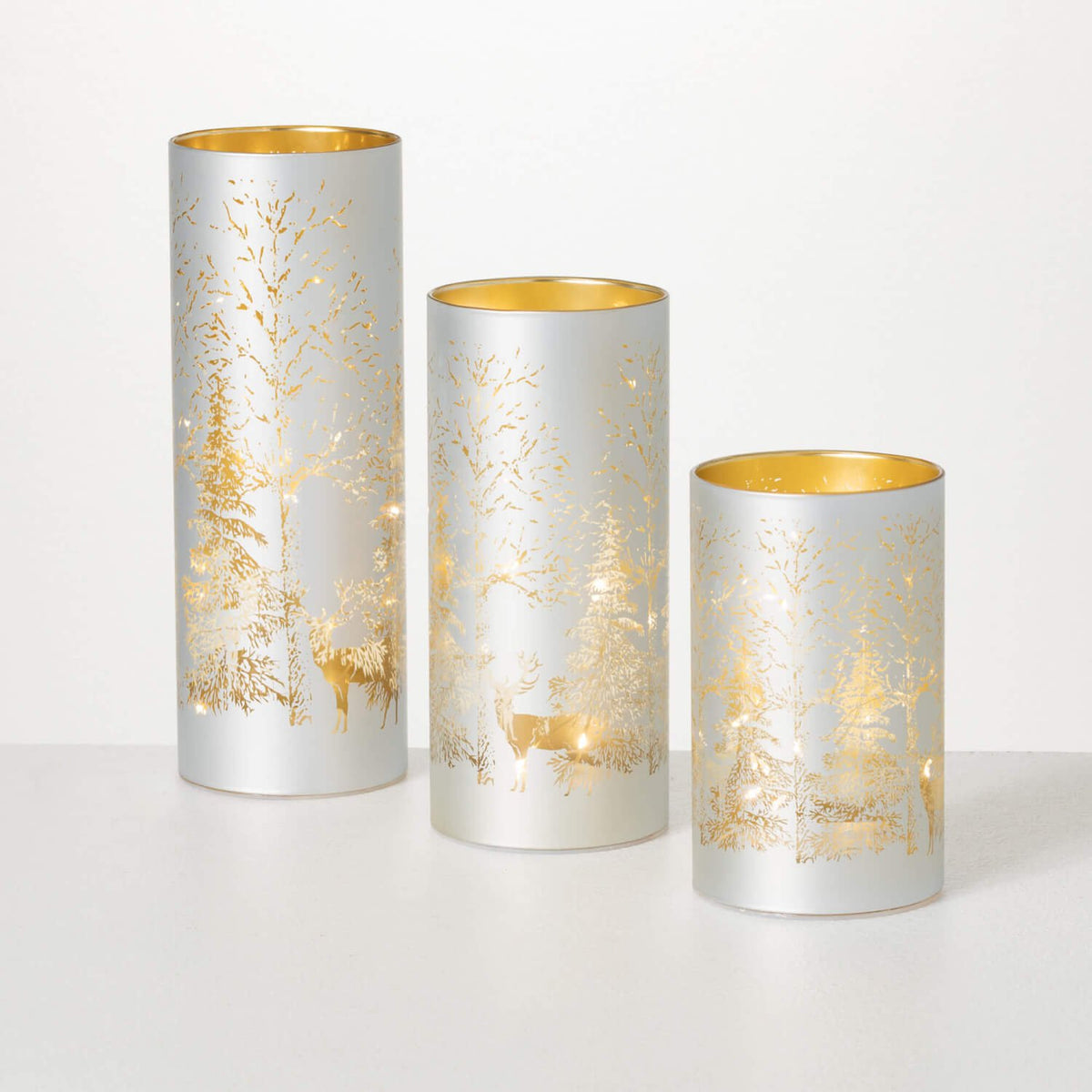 Set of three silver glass cylinders with lighted gold winter forest and deer scenes.