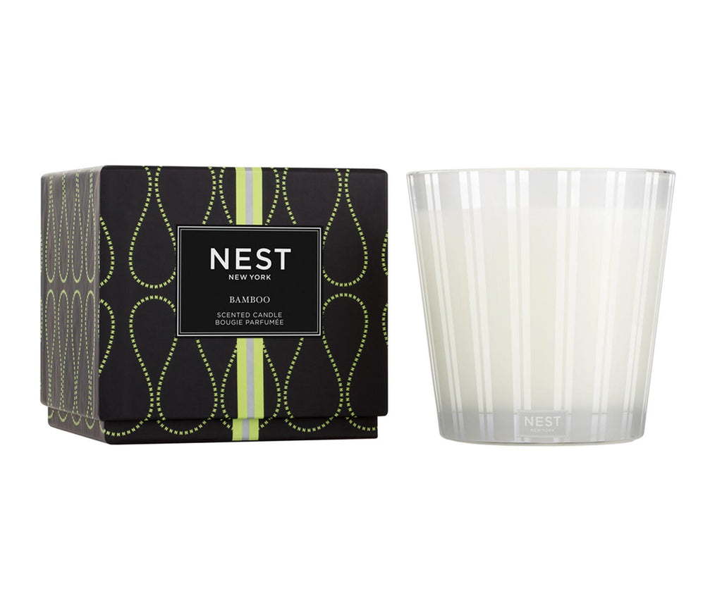 Nest Bamboo 3-wick scented candle in a frosted striped glass jar next to its black patterned box.