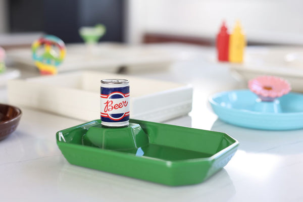 Green ceramic serving tray with a miniature beer can decoration in the center.