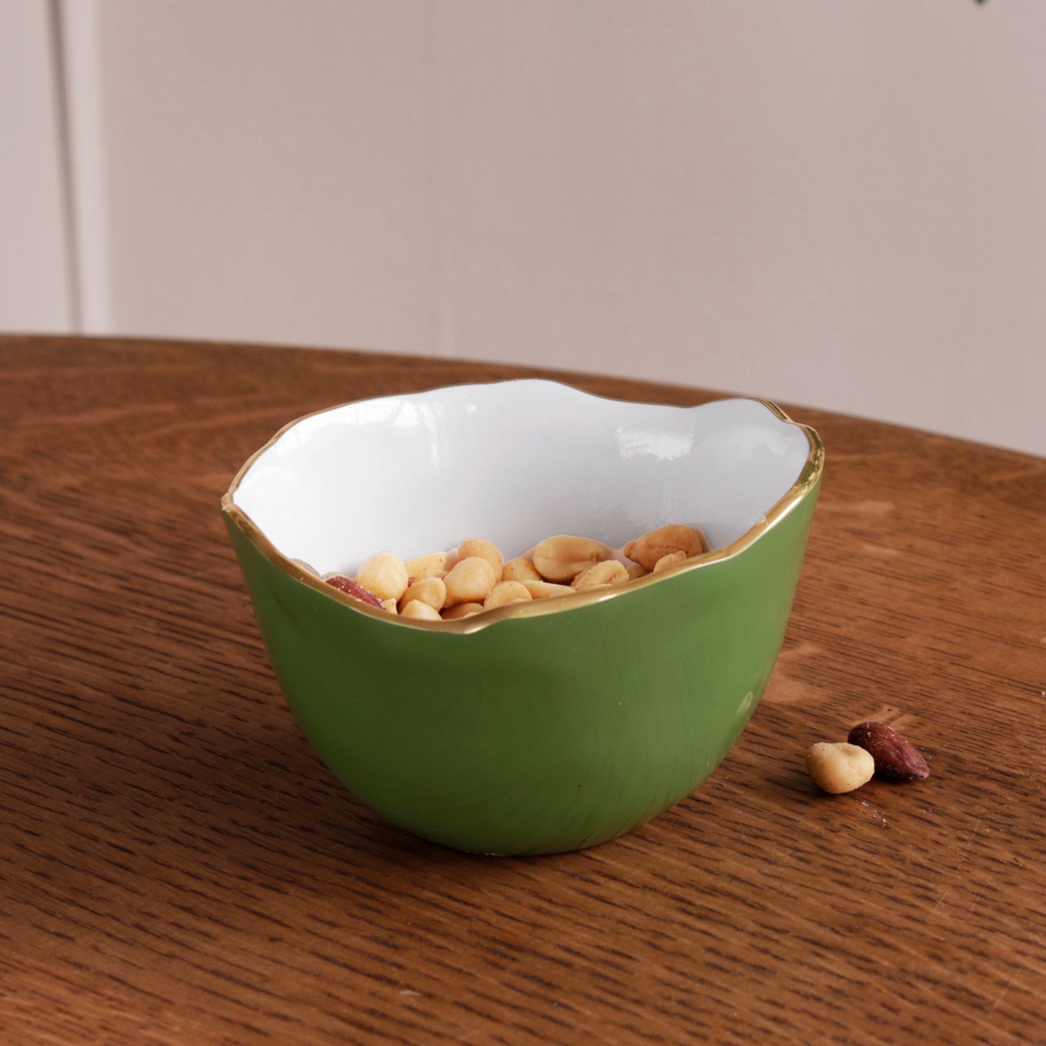 Encanto Osaka small leaf green and white bowl with gold rim, filled with peanuts on a wooden table.