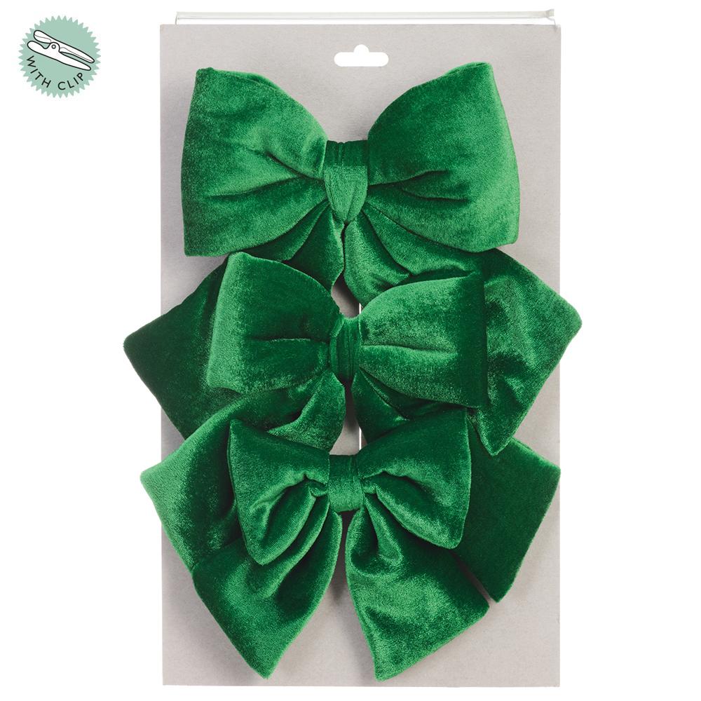Set of three emerald green velvet bows with clips attached to a grey display card.