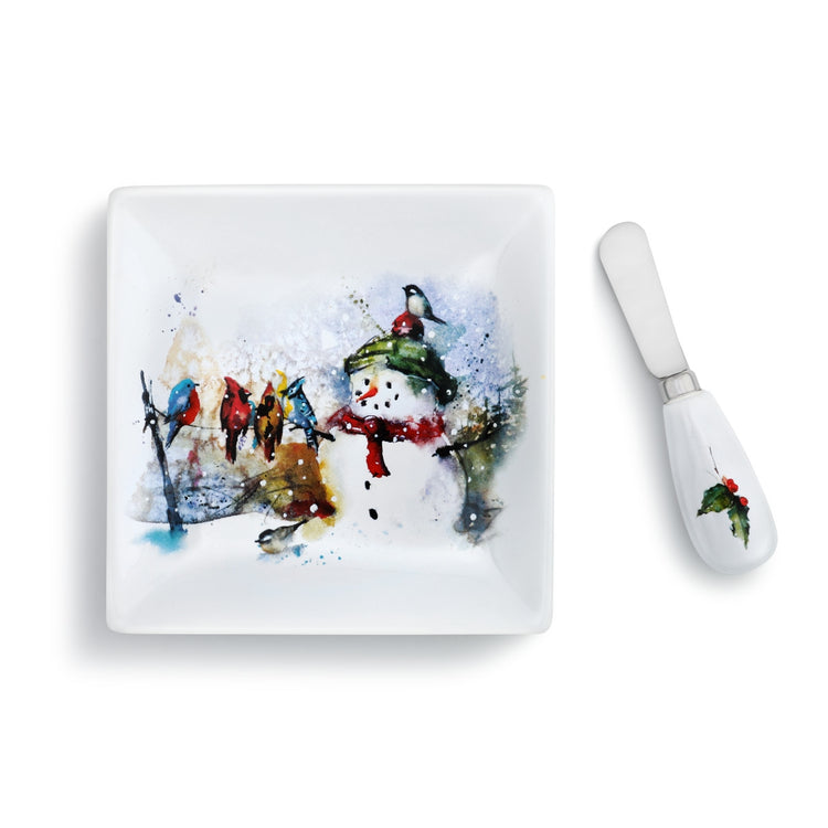 White square plate with a watercolor snowman and birds design, paired with a white spreader with a holly accent.