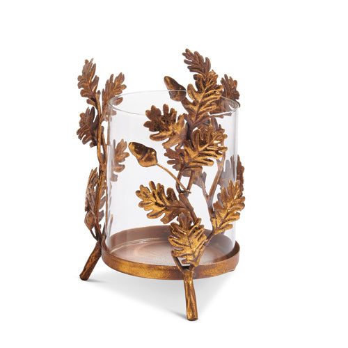 Gold oak leaf iron base with clear glass insert holding a pillar candle