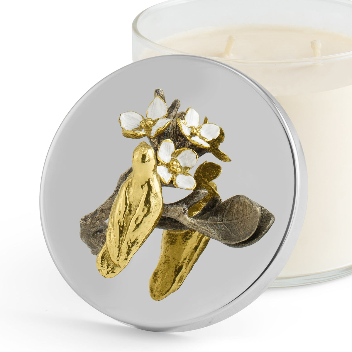 White enamel glass candle in natural brass with white four-petaled flowers on a branch silhouette.