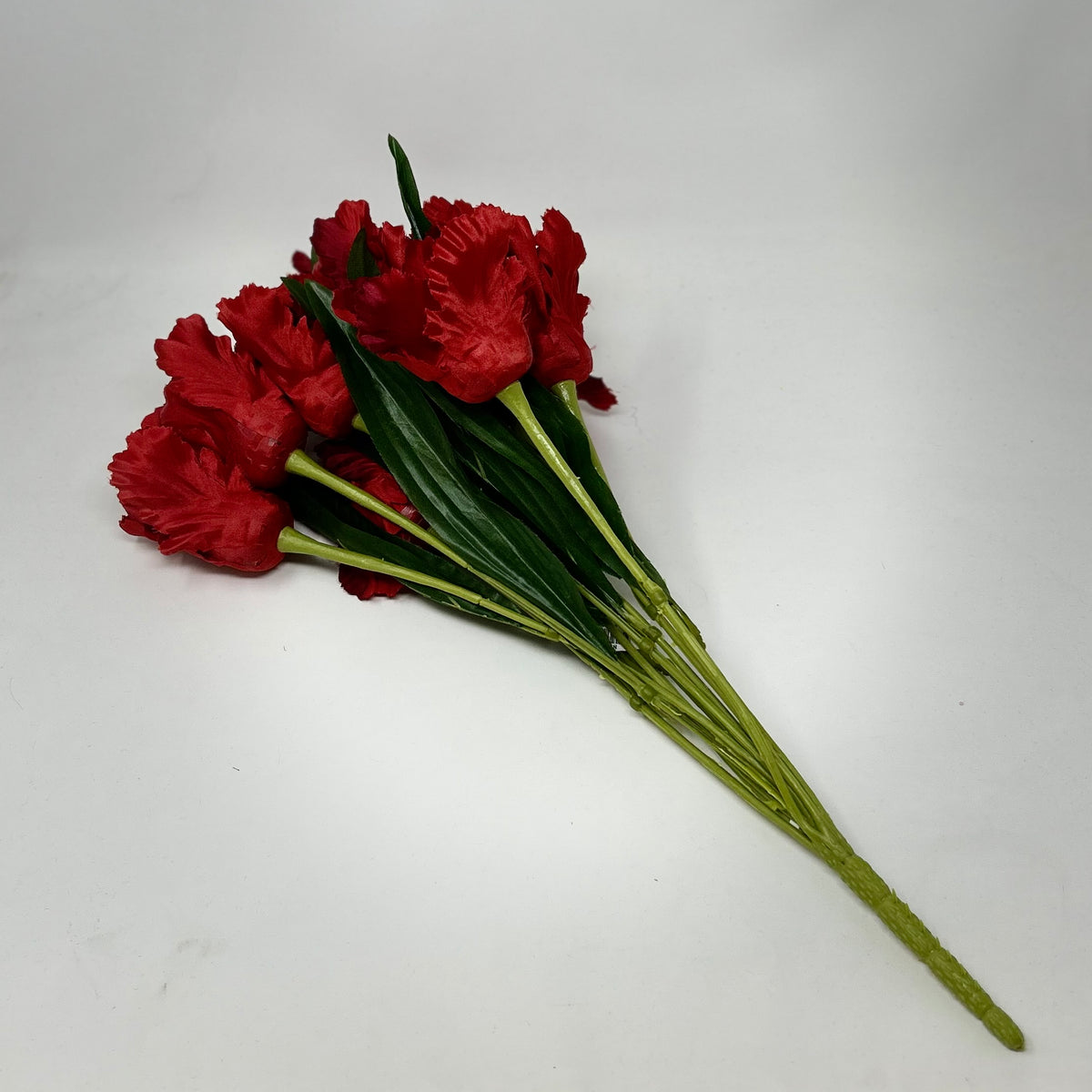 A bouquet of 12 red artificial tulips with green stems and leaves on a white background.