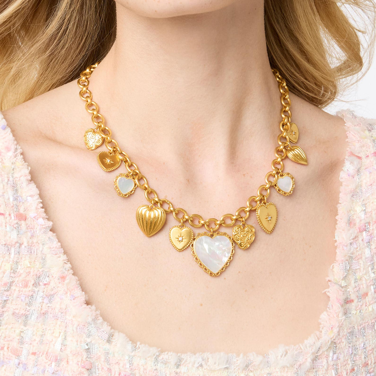 Gold heart charm necklace with mother of pearl and cubic zirconia on a model.