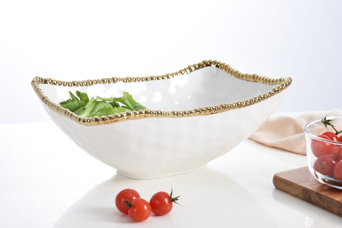 Deep white porcelain serving bowl with gold beaded titanium rim, containing green leaves.