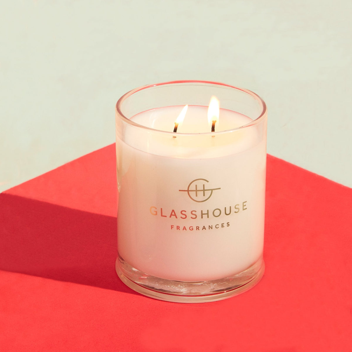 A white cylindrical glass jar containing a beige candle with a single wick.