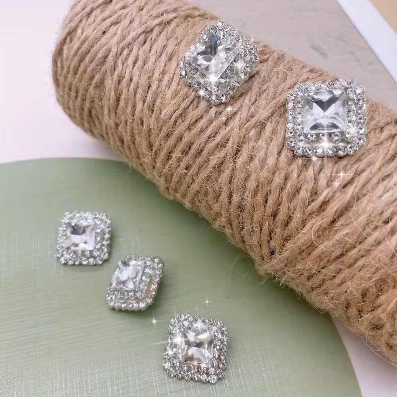 Five square metal buttons with rhinestone accents in a neutral tone