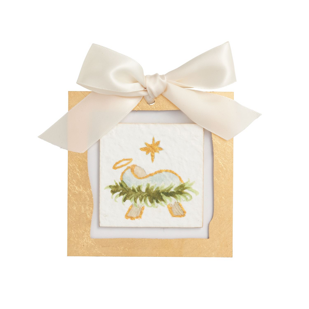 Gold painted acrylic ornament with a nativity scene on recycled paper and a white satin bow.