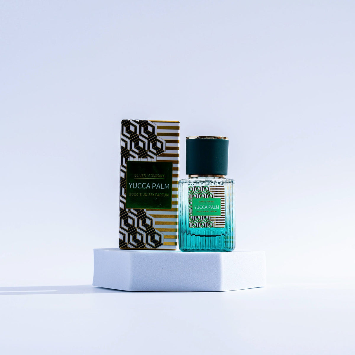 Yucca Palm Fragrance Mist in a teal glass bottle next to its geometric patterned box on a pedestal.