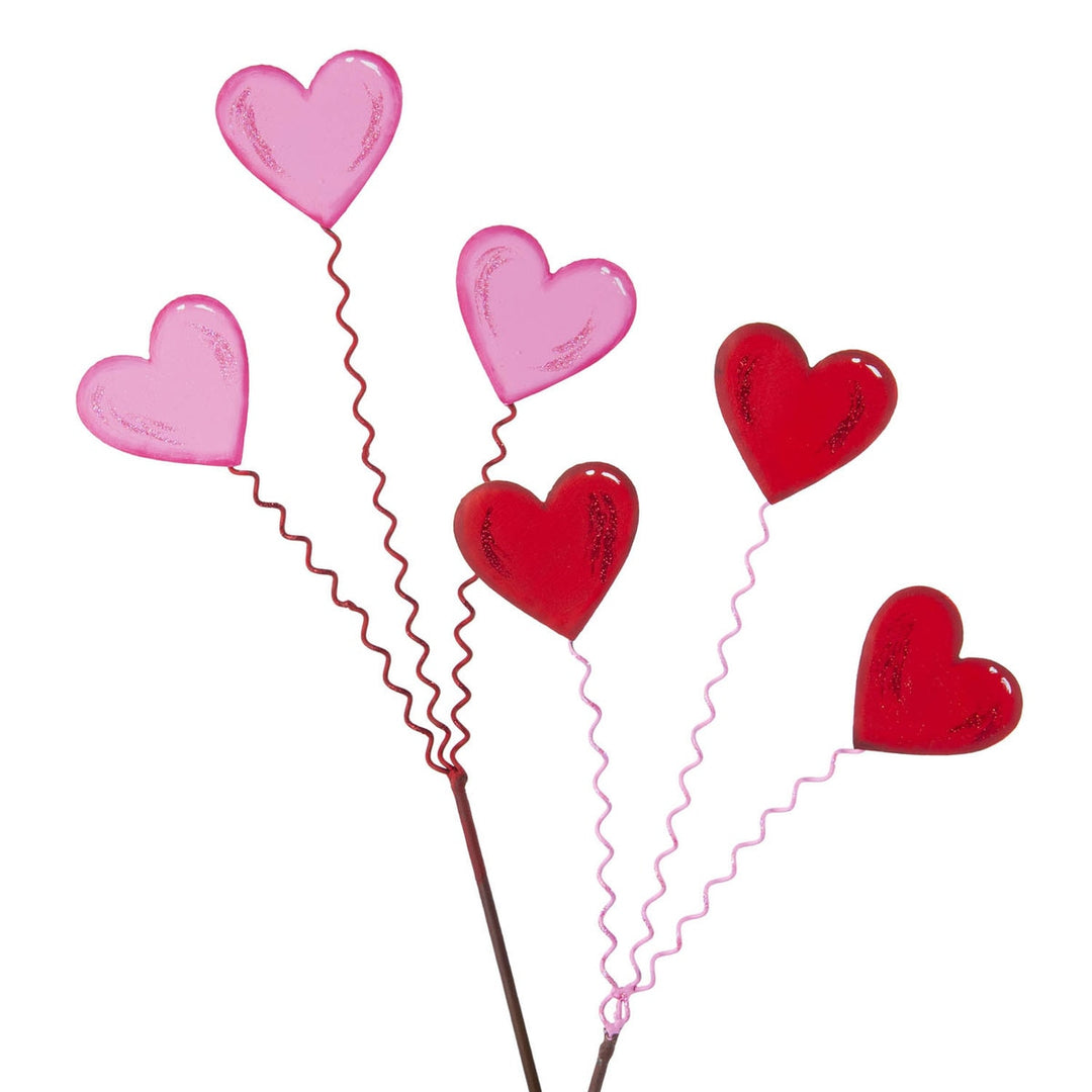 Three heart-shaped stakes with matte finish designed to hold flowers in outdoor garden settings.