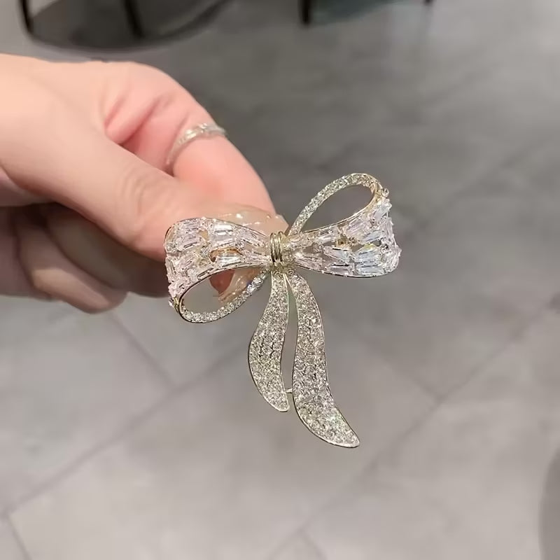 Vintage rhinestone bow brooch pin with a metallic gold-tone finish.