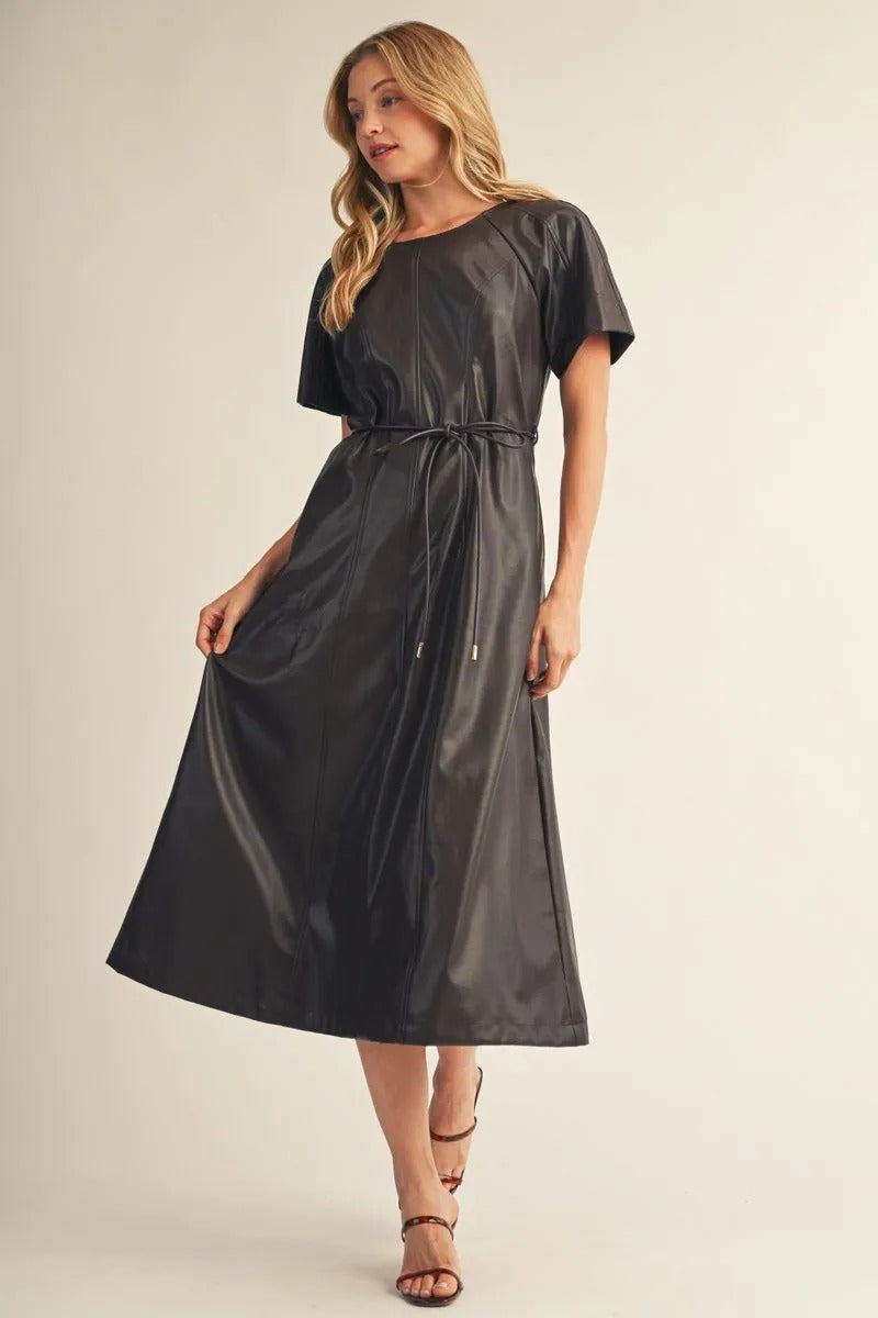 Woman wearing the Allison short sleeve faux leather midi dress in black with a tie waist.