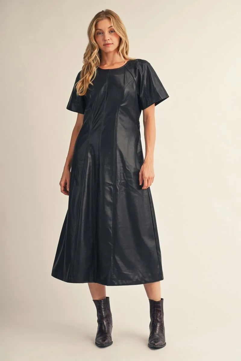 Woman wearing the Allison black short-sleeve faux leather midi dress with black ankle boots.