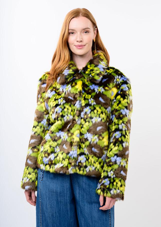 Woman wearing a Sophia Floral Faux Fur Jacket in green, blue, and brown with blue jeans.
