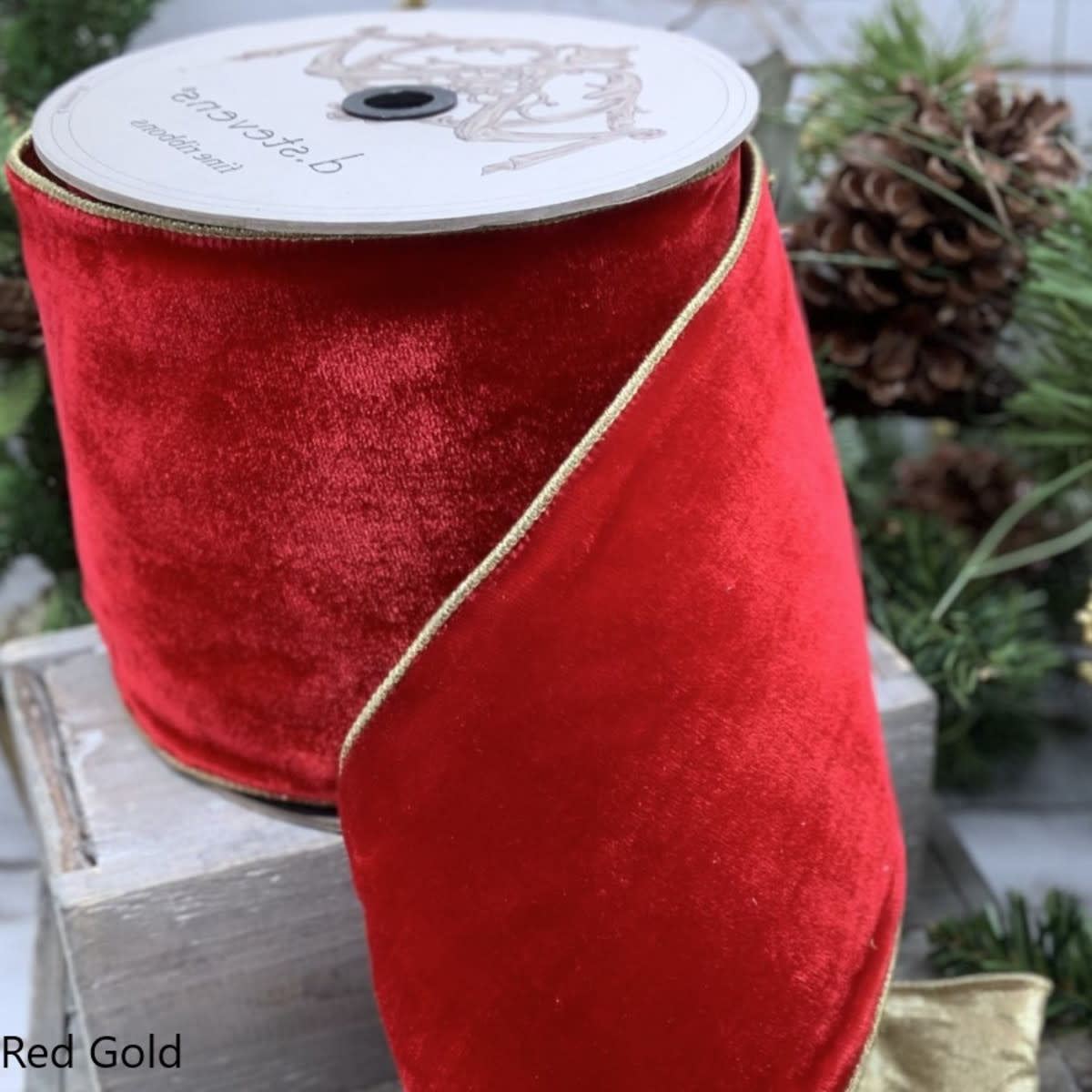 A roll of 2.5-inch wide red velvet ribbon with gold metallic edges.
