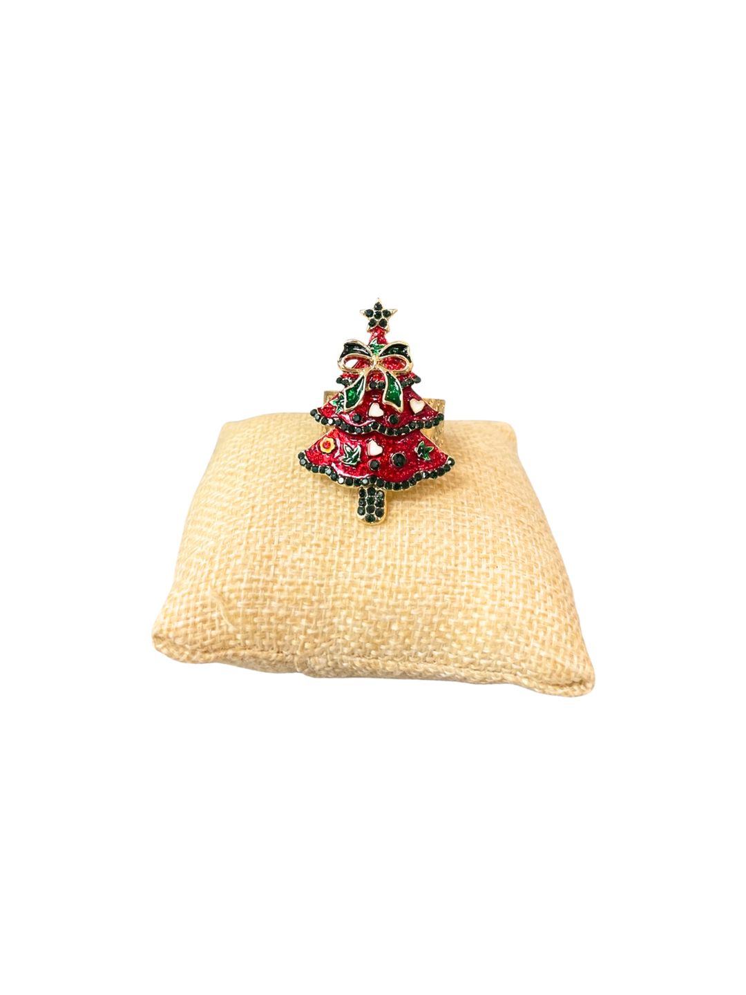 Red and green enamel Christmas tree ring with gold accents on a small burlap display pillow.