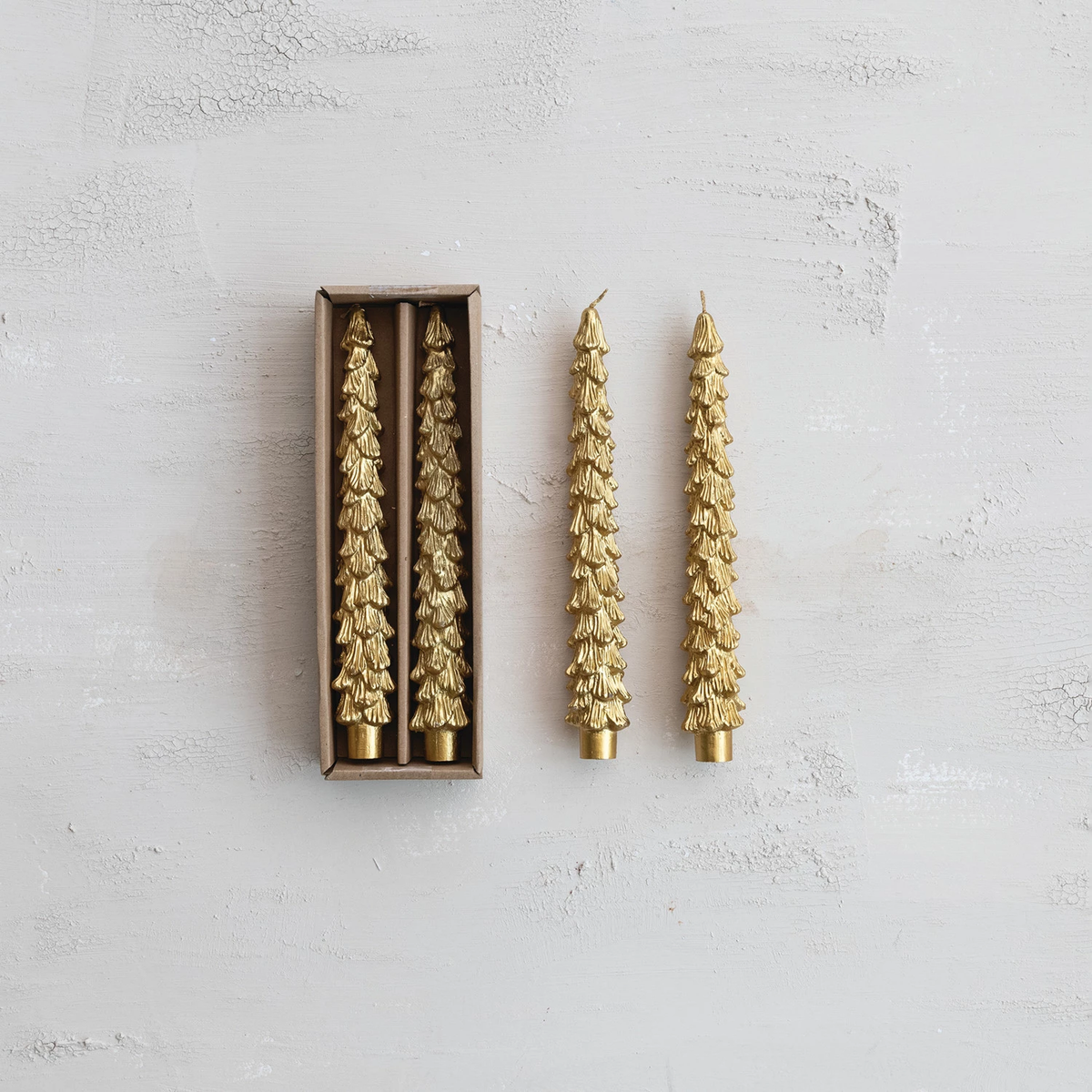 Set of four gold unscented tree-shaped taper candles, two in a box and two standing beside it.