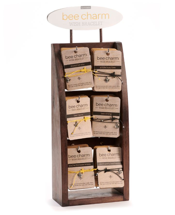 Wooden display stand holding six varieties of bee charm wish bracelets on yellow and black cords.
