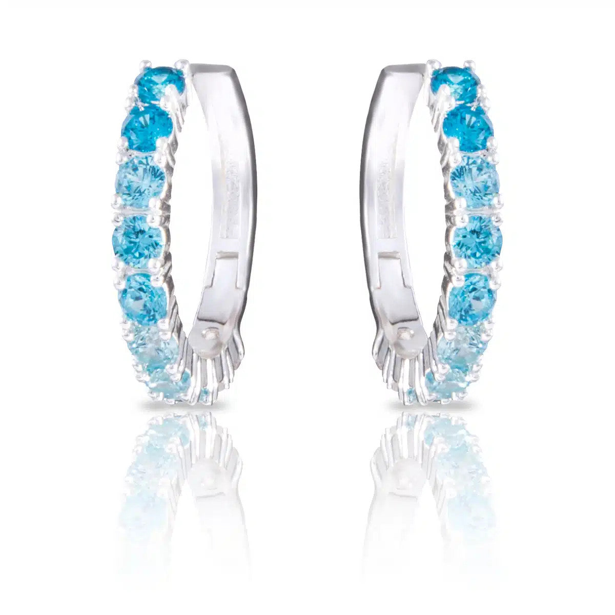 Silver huggie hoop earrings featuring a gradient of light to dark blue cubic zirconia stones.