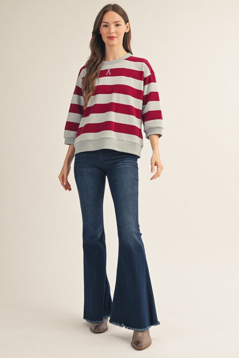 Woman wearing the Roxanne V-Notched Bold Stripe Casual Top in red and grey with flare jeans.