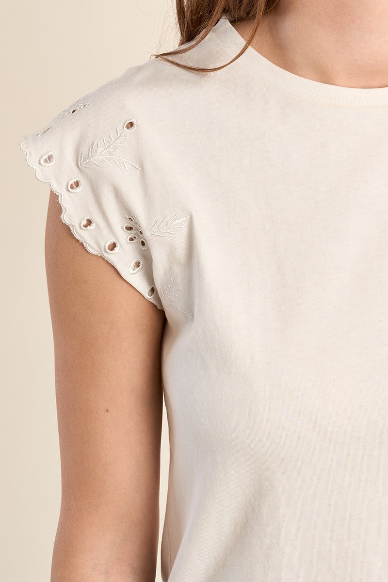 Close-up of a white cotton Madison tee featuring scalloped, embroidered eyelet short sleeves.