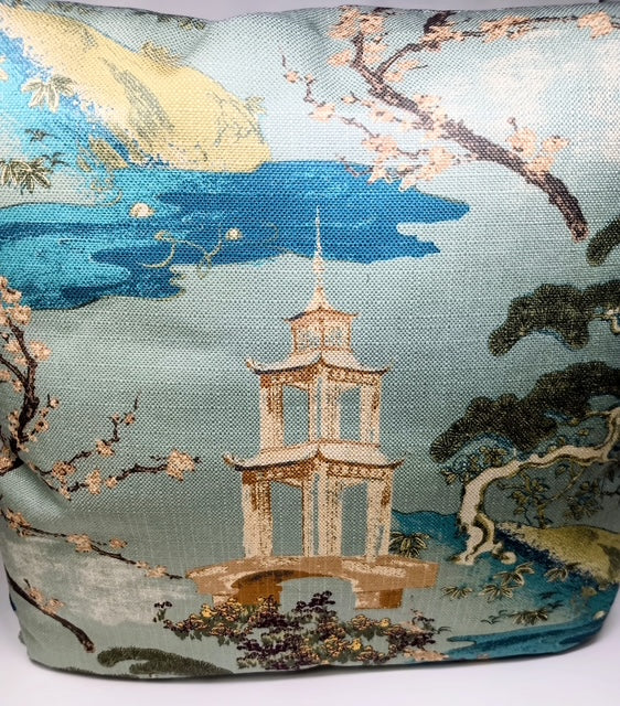 A hand-crafted pillow featuring a serene Asian landscape with a pagoda, bridge, cherry blossoms, and mountains.