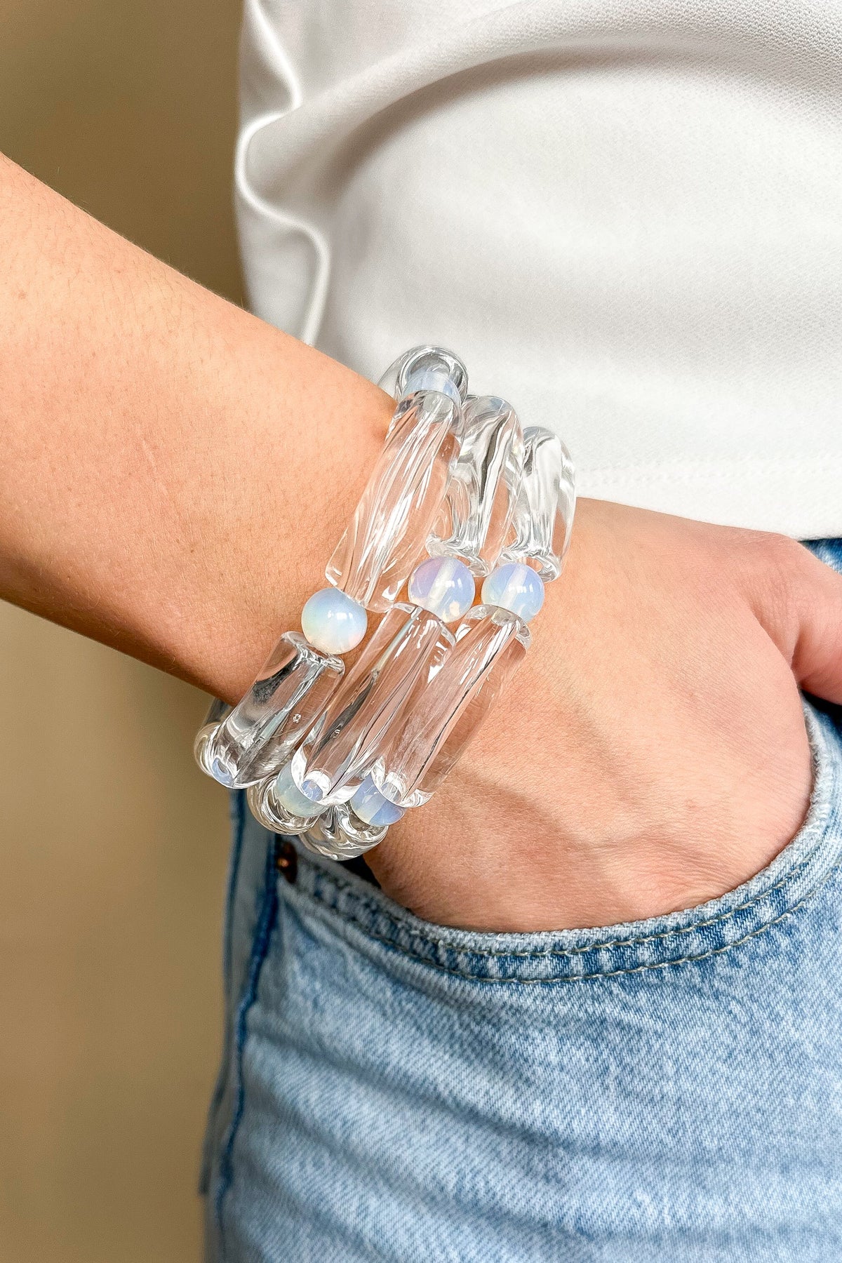 WS Emmy Bracelet: A stack of three clear acrylic tube bracelets with iridescent opal-like beads.