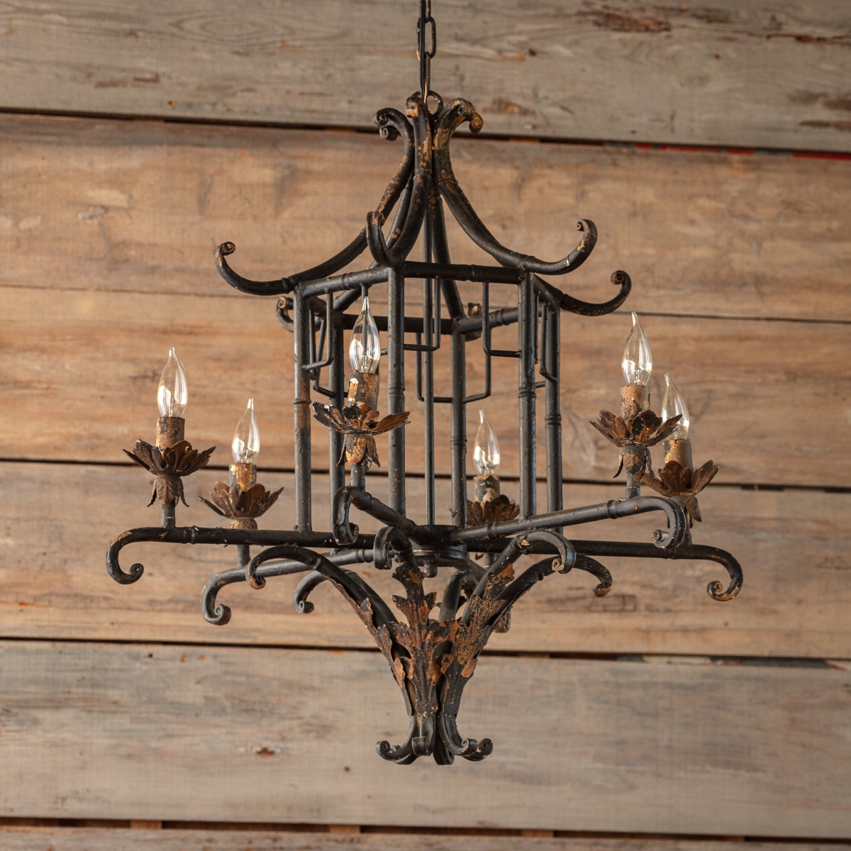 Aged iron pagoda chandelier with a tiered geometric silhouette.