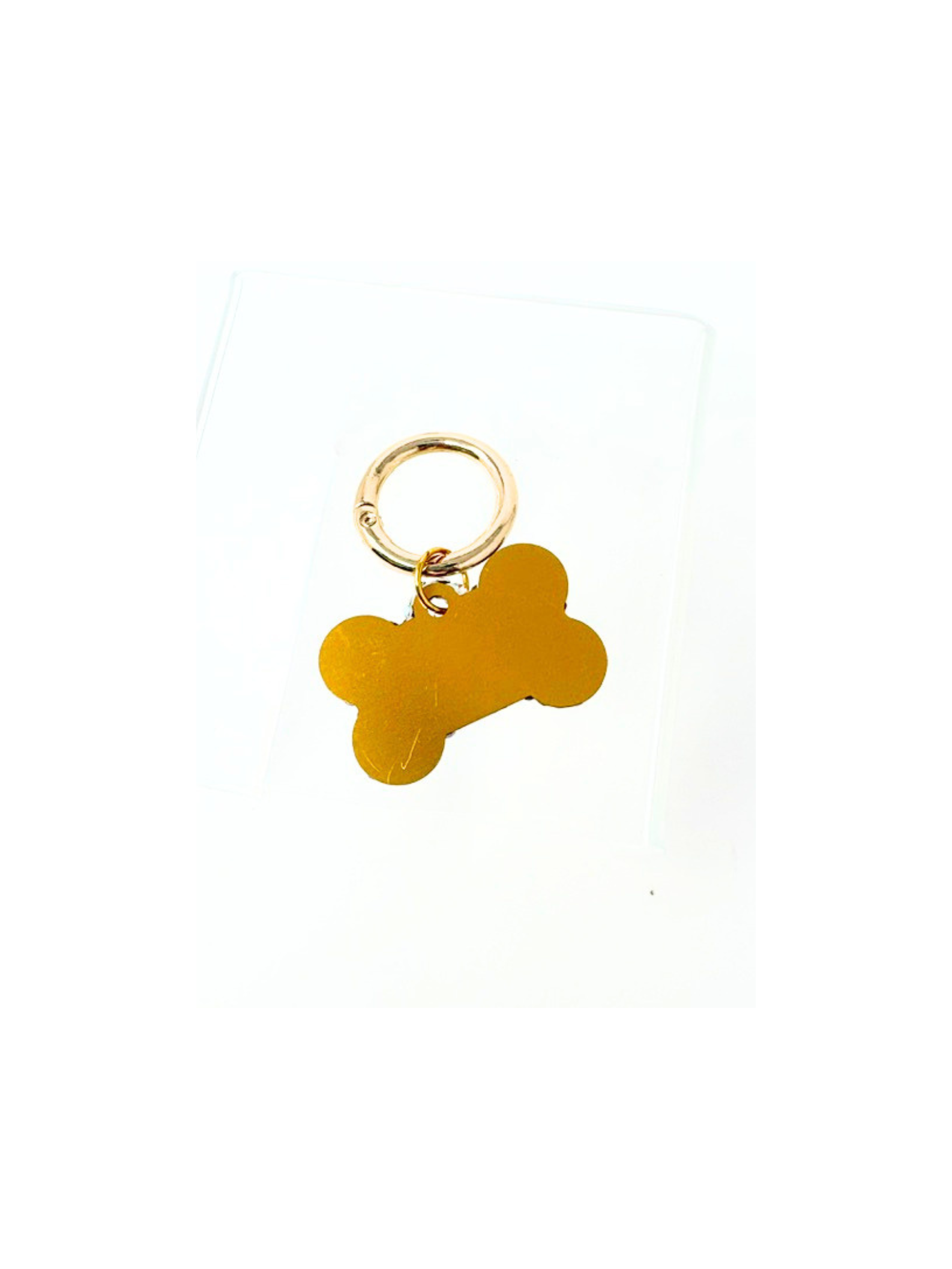 Gold bone-shaped dog tag with a solid engravable surface and a circular metal clip.