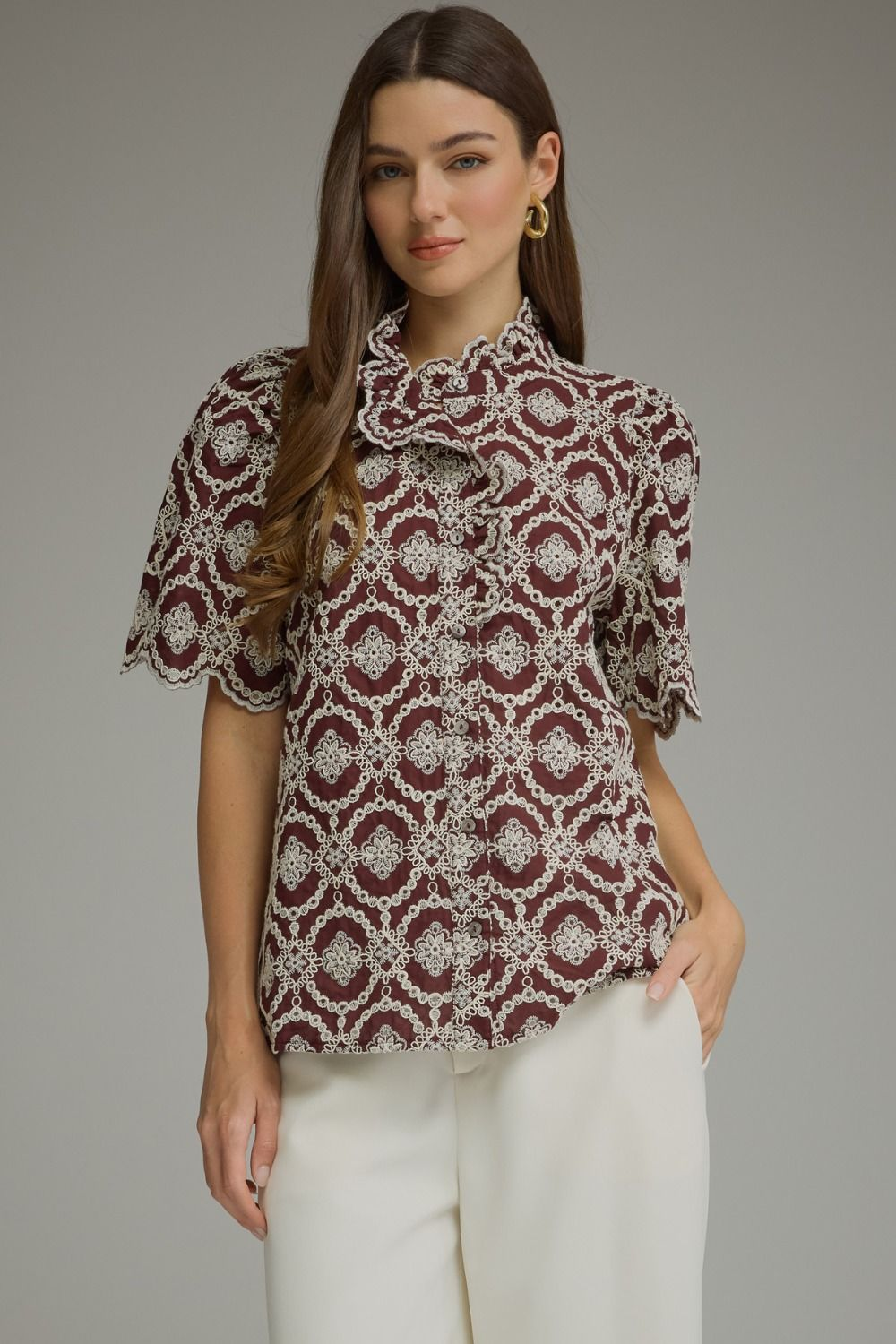 Woman wearing the Amalia burgundy geometric embroidered short puff sleeve top with ruffled neckline.
