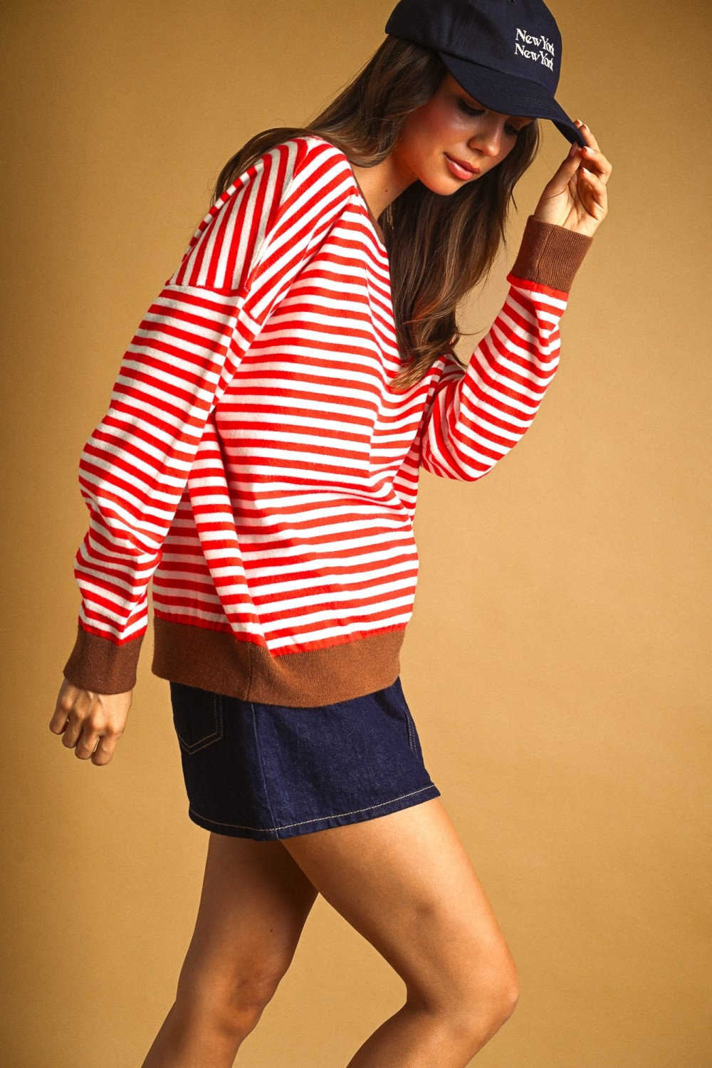 Woman wearing the Alessia red and white striped knit top with brown contrast trim and denim skirt.