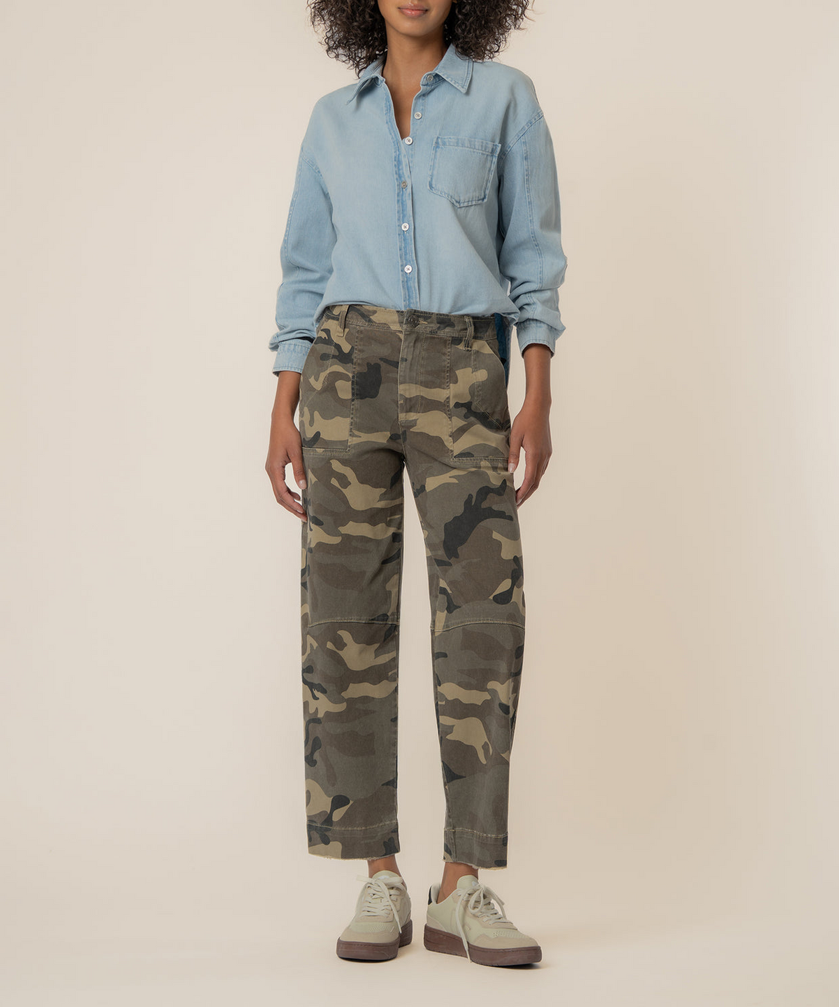 Woman wearing Ashton Wide Leg Barrel camo pants with a light blue denim shirt and sneakers.
