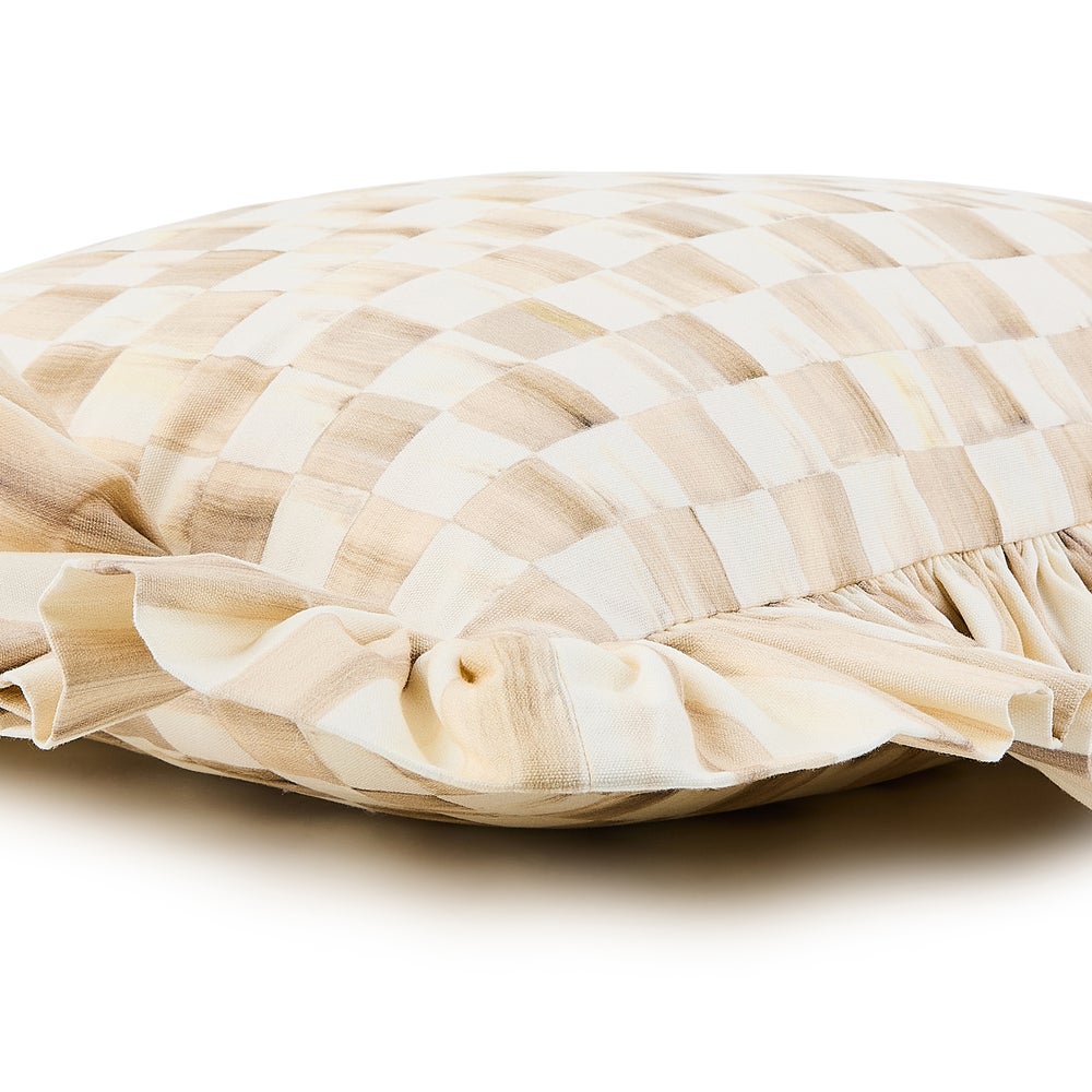 Close-up of a mocha and white checkered cotton throw pillow with a ruffled edge.