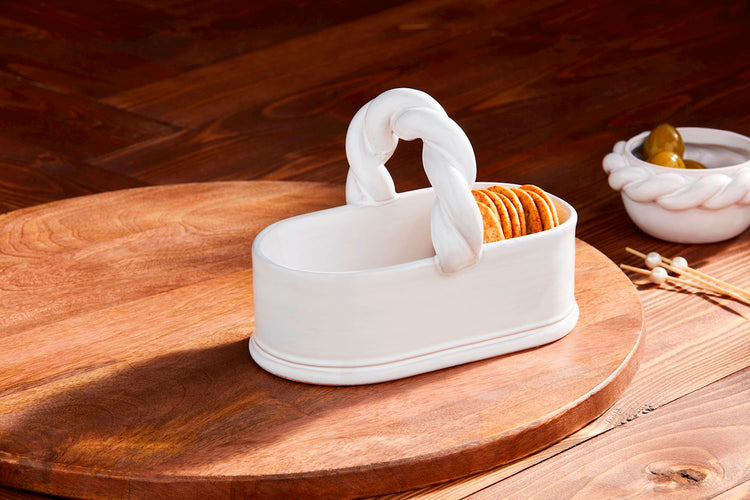 White terracotta Twisted Handle Tidbit basket holding crackers on a wooden serving board.