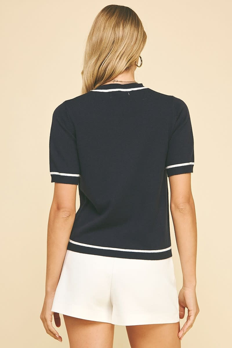 Back view of Magda short-sleeve sweater in dark fabric with contrasting trim at neckline and hem.