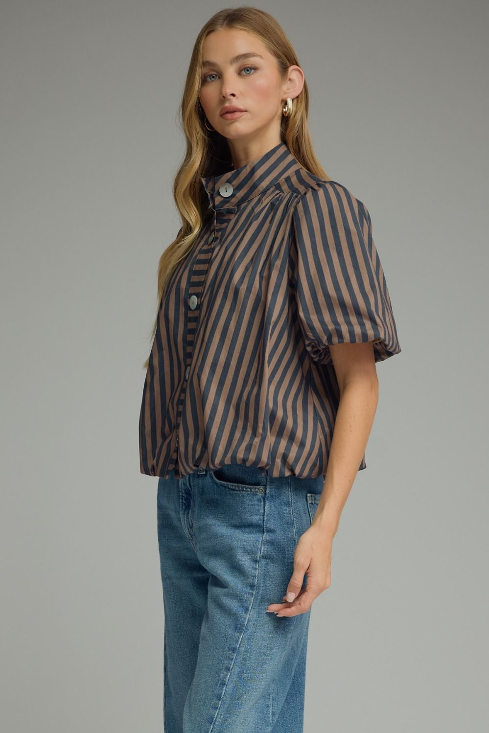 Woman wearing a brown and navy Camila Stripe Short Puff Sleeve Top with blue jeans.