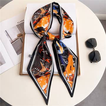 Fashionable double-layer head scarf with orange, black, and blue patterns on a white table.