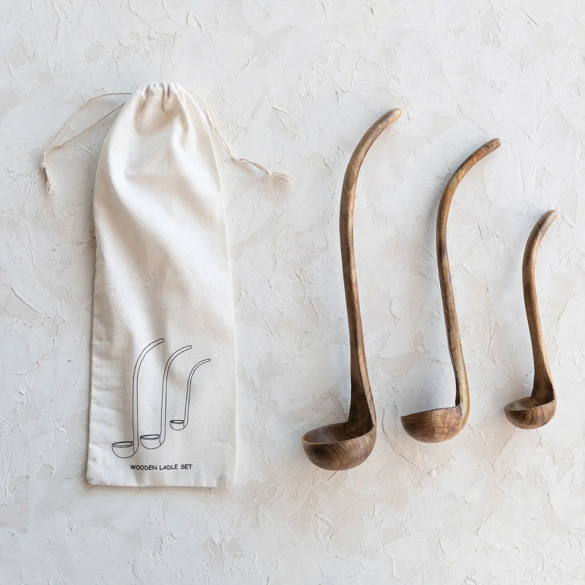 Set of three Scandinavian-inspired mango wood ladles with walnut finish in descending sizes inside a printed drawstring bag.