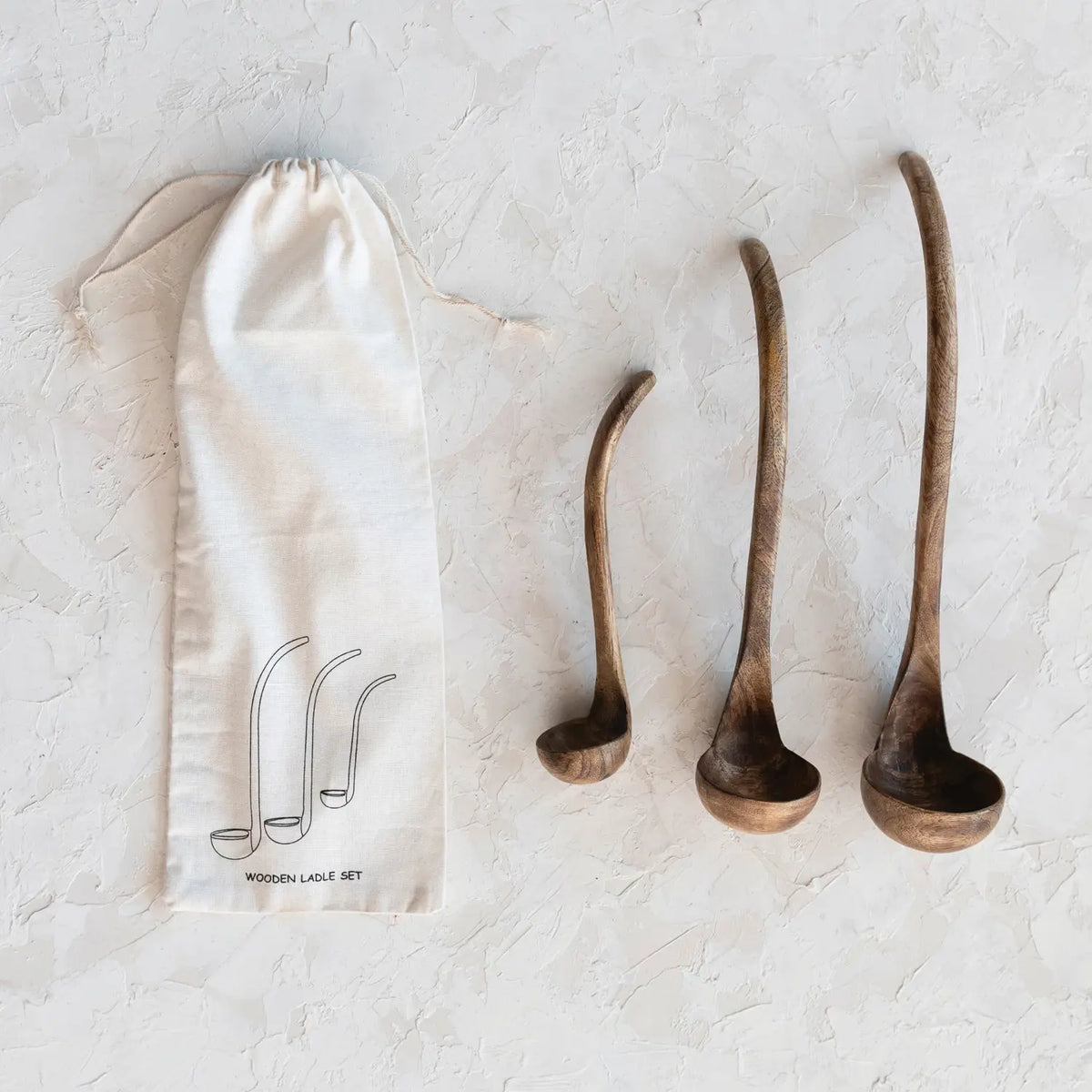 Set of three Scandinavian-inspired mango wood ladles in walnut finish with contemporary silhouettes.