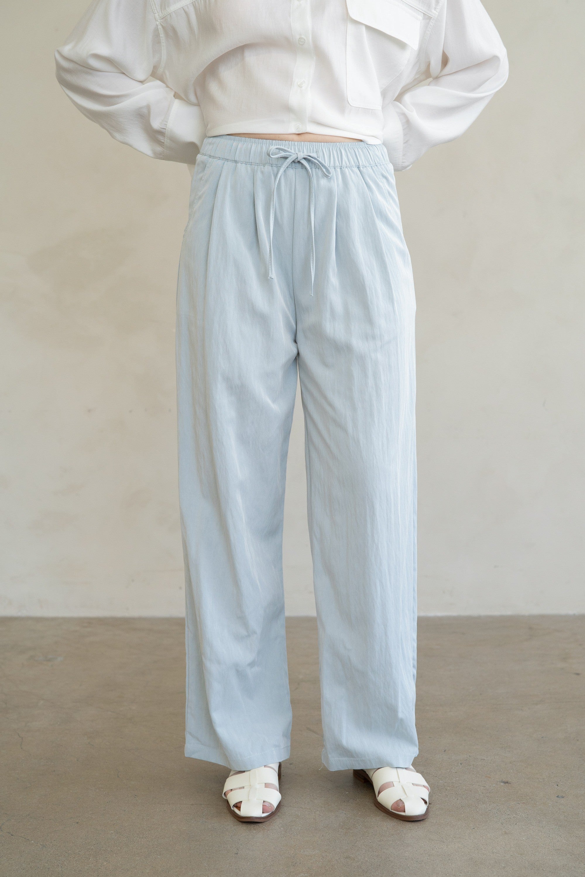 Person wearing Aurora light blue wide-leg drawstring pants with a white button-up shirt.