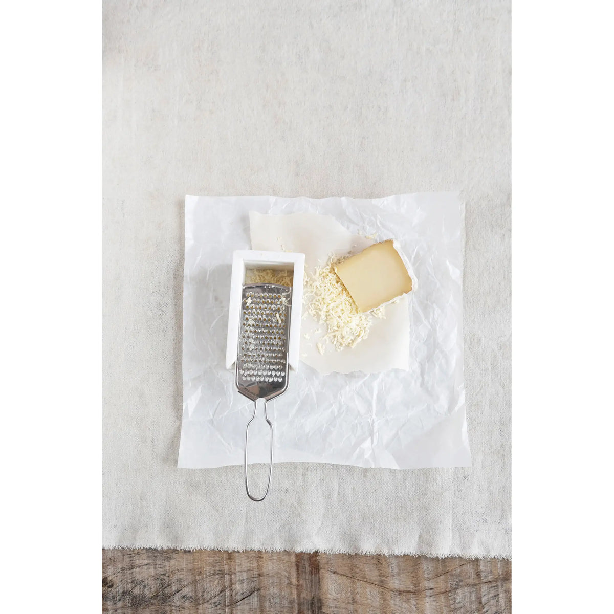 Stainless steel cheese grater with white marble rest