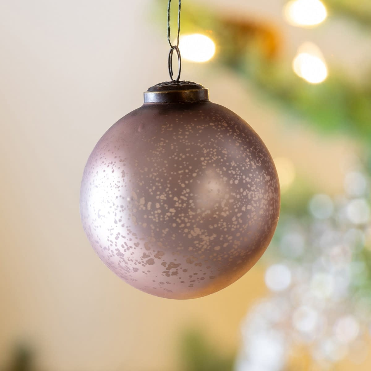 Matte light gold glass ball ornament with vintage holiday sparkle on a cream background.