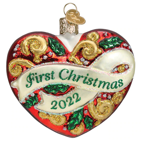 Red heart-shaped glass ornament with gold glitter swirls and 'First Christmas 2022' on a white banner